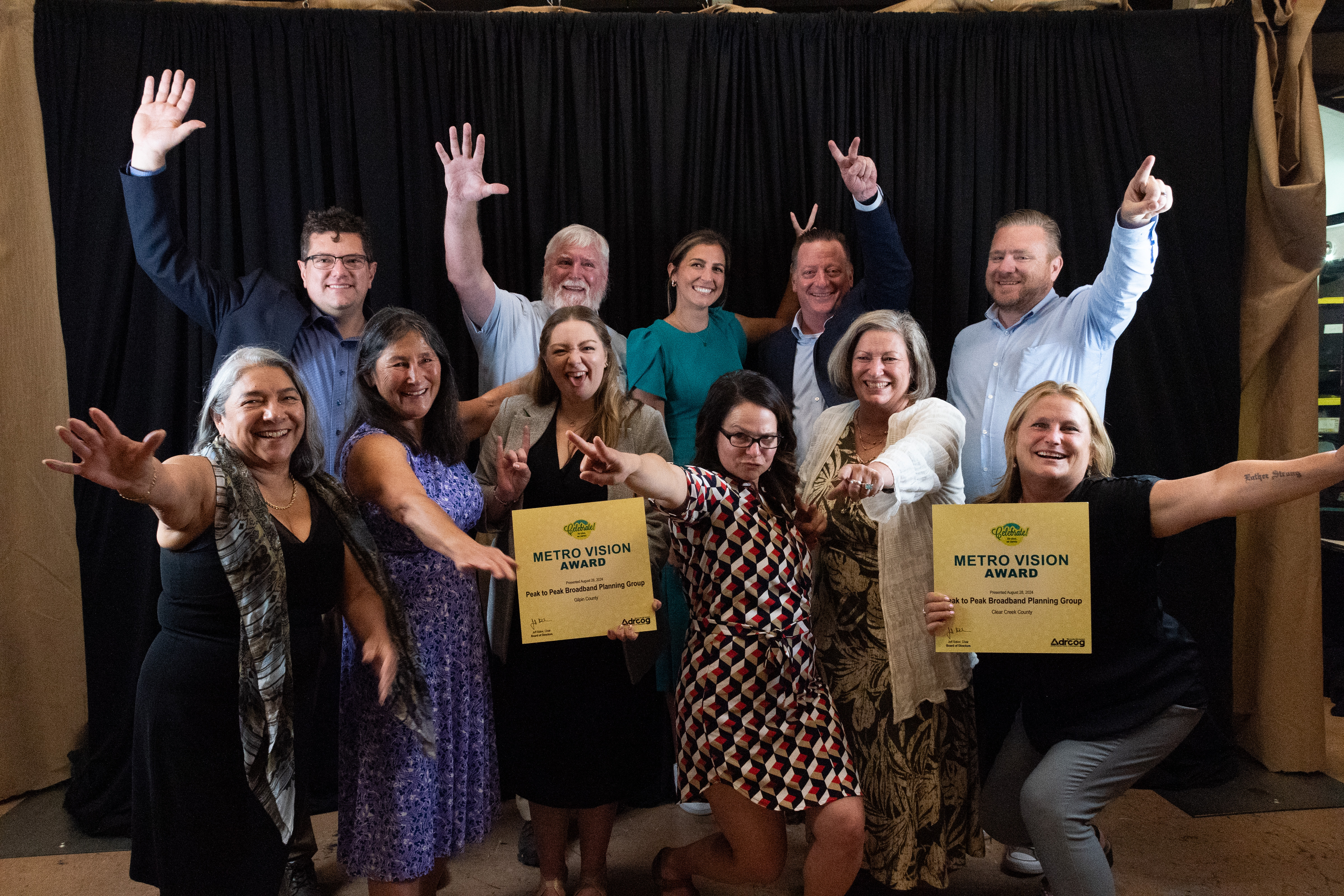 A group of 11 award winners hold their awards and make silly gestures and faces.