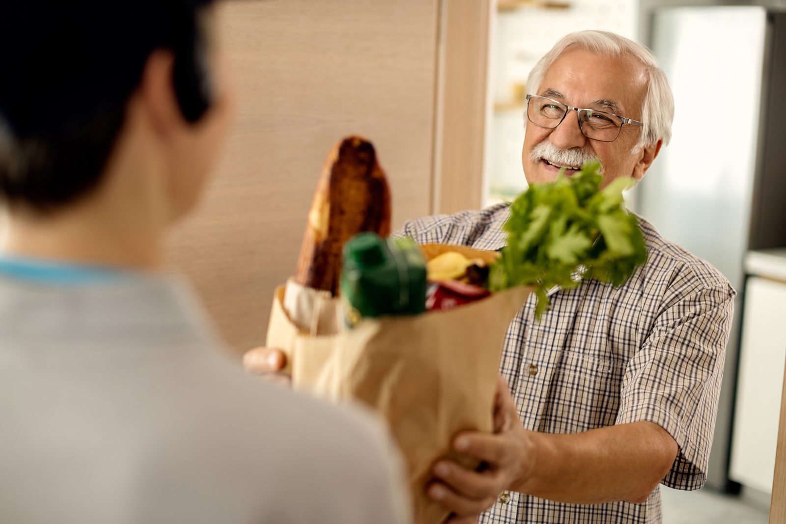 An older adult man receives groceries from a community-based organization.