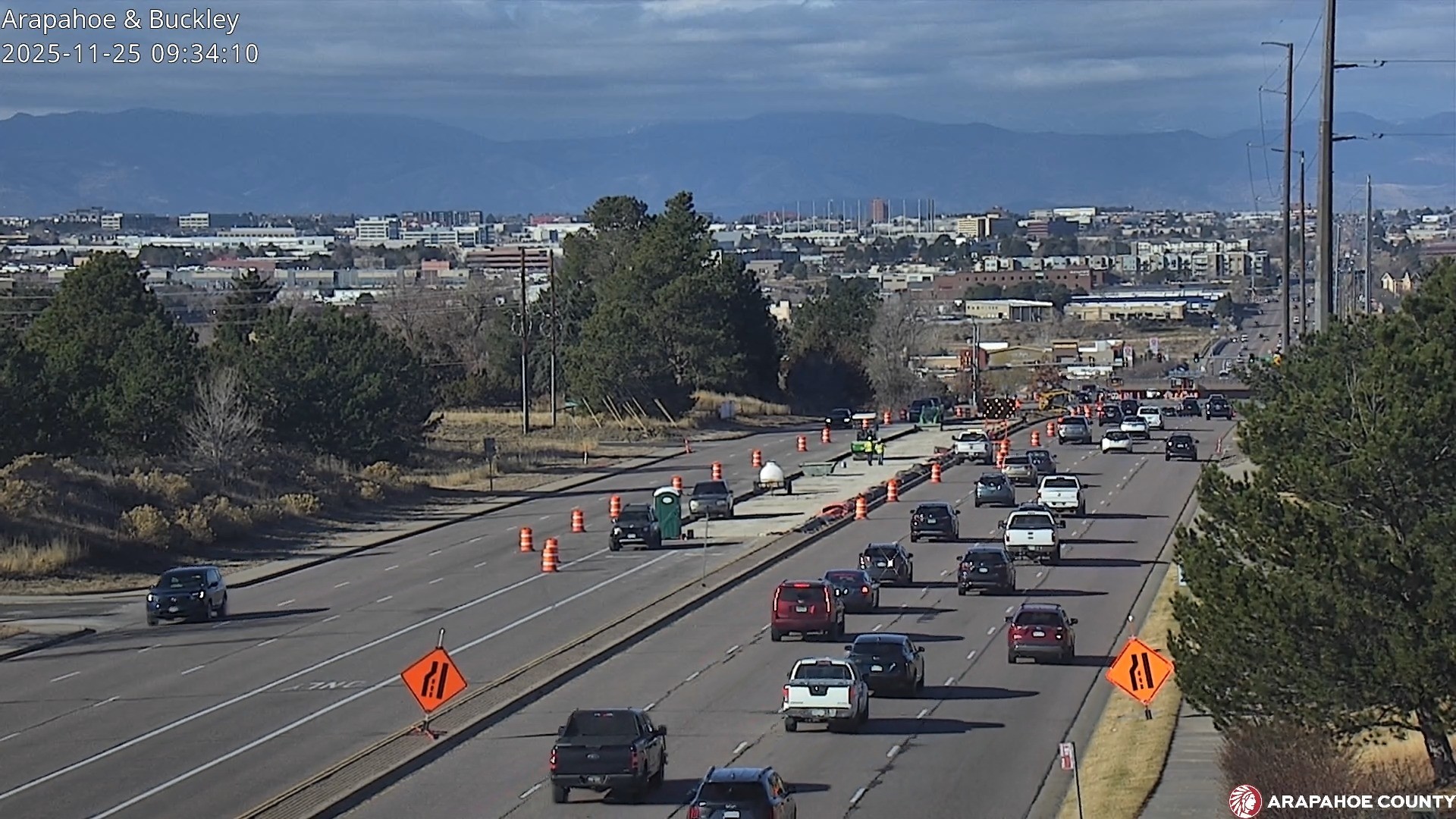 Aerial image of Arapahoe Road with vehicle traveling on the corridor and mountains and tall buildings in the foreground.