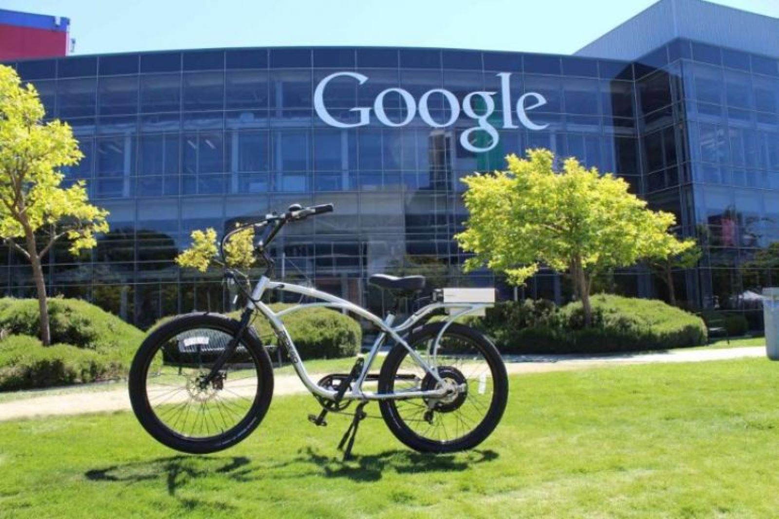 A bicycle on a green lawn in front of a Google building.