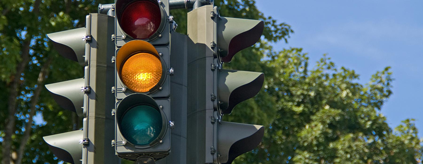 A  three-tiered traffic signal with the middle signal, a yellow light activated.