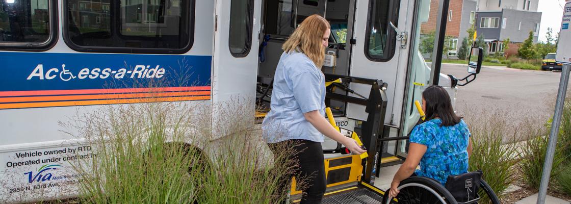 A bus driver lowers the wheelchair ramp to allow a passenger who uses a wheelchair to board the bus.