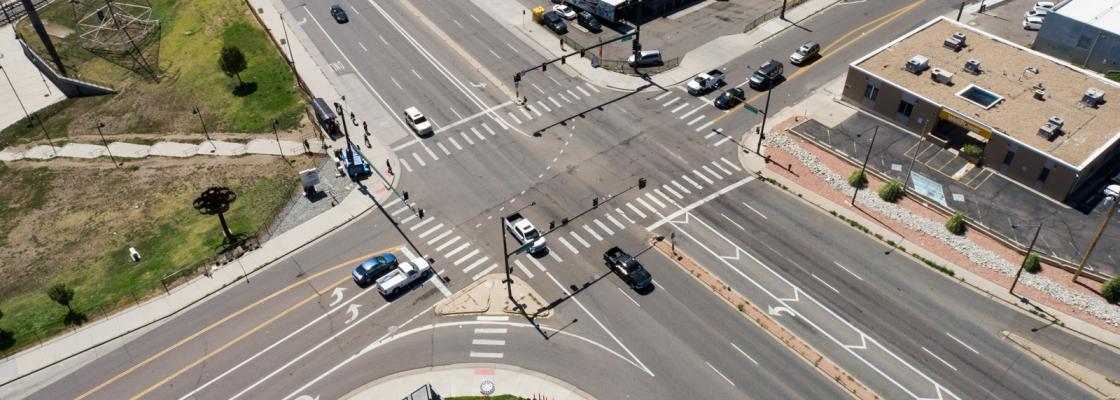 An aerial view of several cars at the intersection of two large roads.