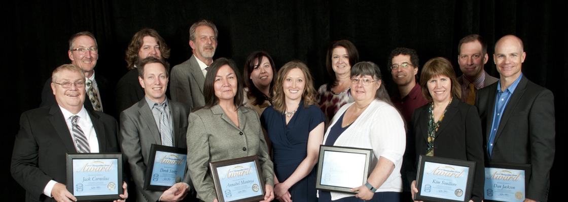 A group of business-casual attired professionals stands in two rows, holding awards for founding the Denver Regional Data Consortium.