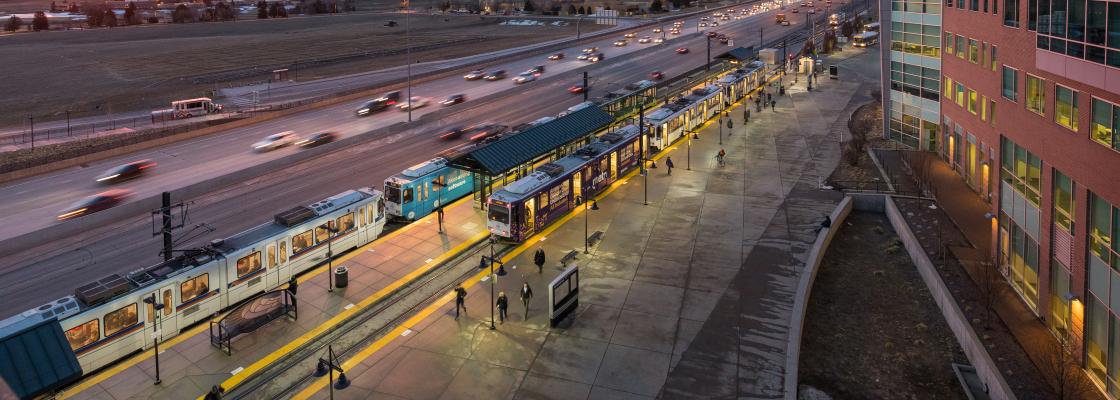 Light rail at Lincoln Station with vehicles traveling on the interstate in the foreground.